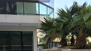 A modern outdoor swimming pool with a water feature, surrounded by a stone wall and palm trees. - Riviera: M4 Giardino 44A, Beach front (Bertioga)