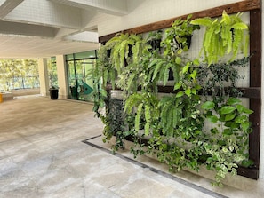 A lobby with a large indoor plant wall, a tiled floor, and a glass entrance. - Riviera: M4 Giardino 44A, Beach front (Bertioga)