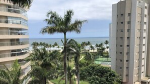 A high-rise building with multiple balconies overlooking a beach and ocean. - Riviera: M3 Kingston Town 61, beach front (Bertioga)