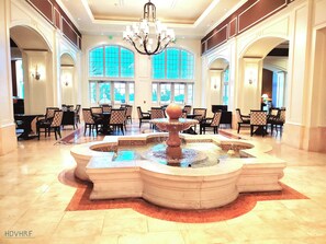 A lobby with a fountain, seating areas, and large windows. - Brand New Modern, Luxury Villa with Resort Pools near Disney! (Kissimmee)
