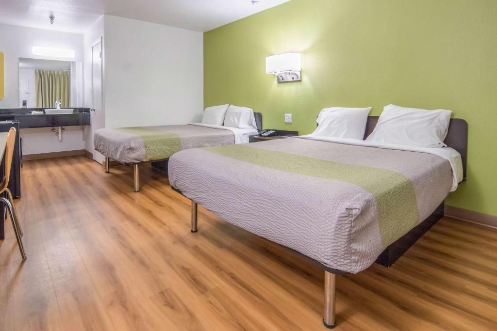 Habitación de hotel con dos camas, un escritorio y una silla.