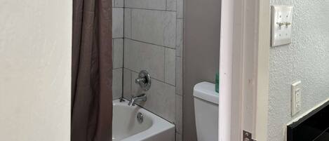 A bathroom with a bathtub, toilet, and a shower curtain.