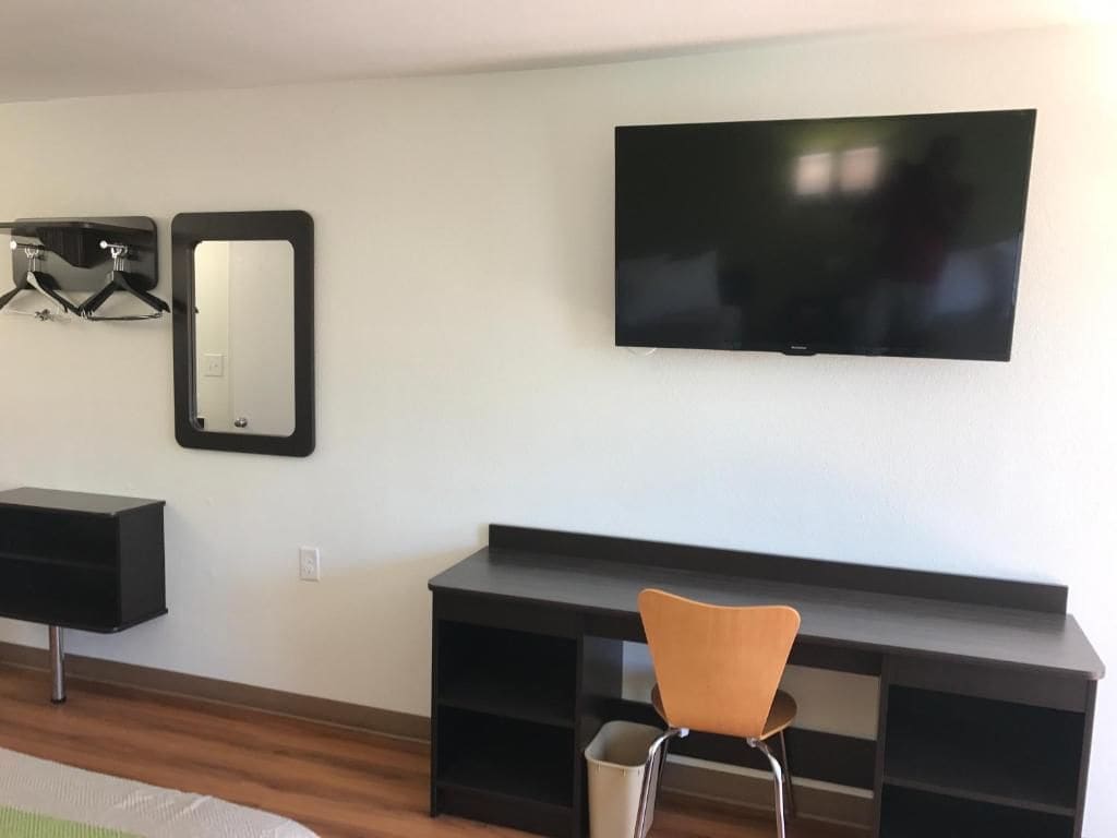 Une chambre d’hôtel équipée d’un téléviseur à écran plat fixé au mur, d’un miroir, d’un bureau et d’une chaise.