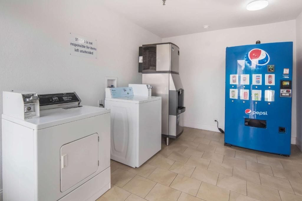 A laundry area with a washing machine, dryer, and a Pepsi vending machine.