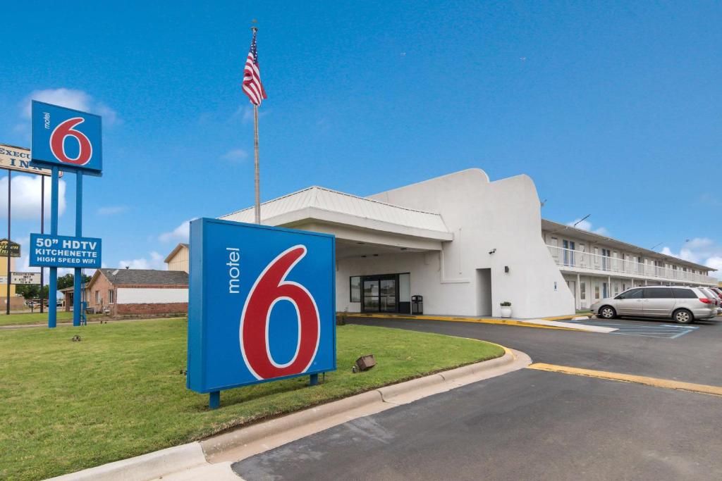 A motel with a prominent '6' sign, a flag, and a sign indicating 50' HDTV and high-speed WiFi.