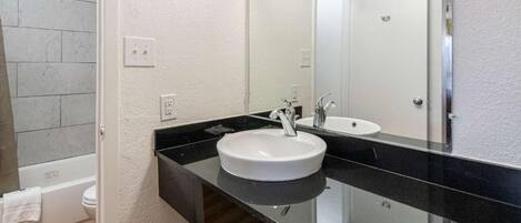 A bathroom with a white sink, a mirror, and a bathtub.