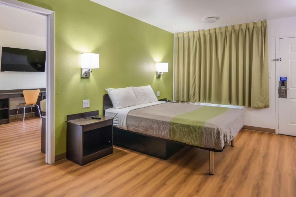 Una habitación de hotel con una cama, lámparas de noche, un televisor y un escritorio con una silla.