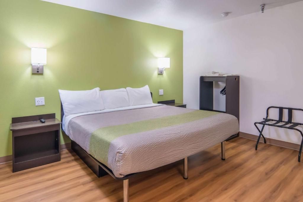 A hotel room with a bed, bedside tables, a chair, and a wardrobe.