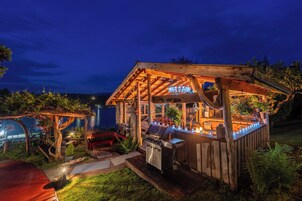 Una estructura de madera al aire libre con una parrilla, asientos y un área cubierta.