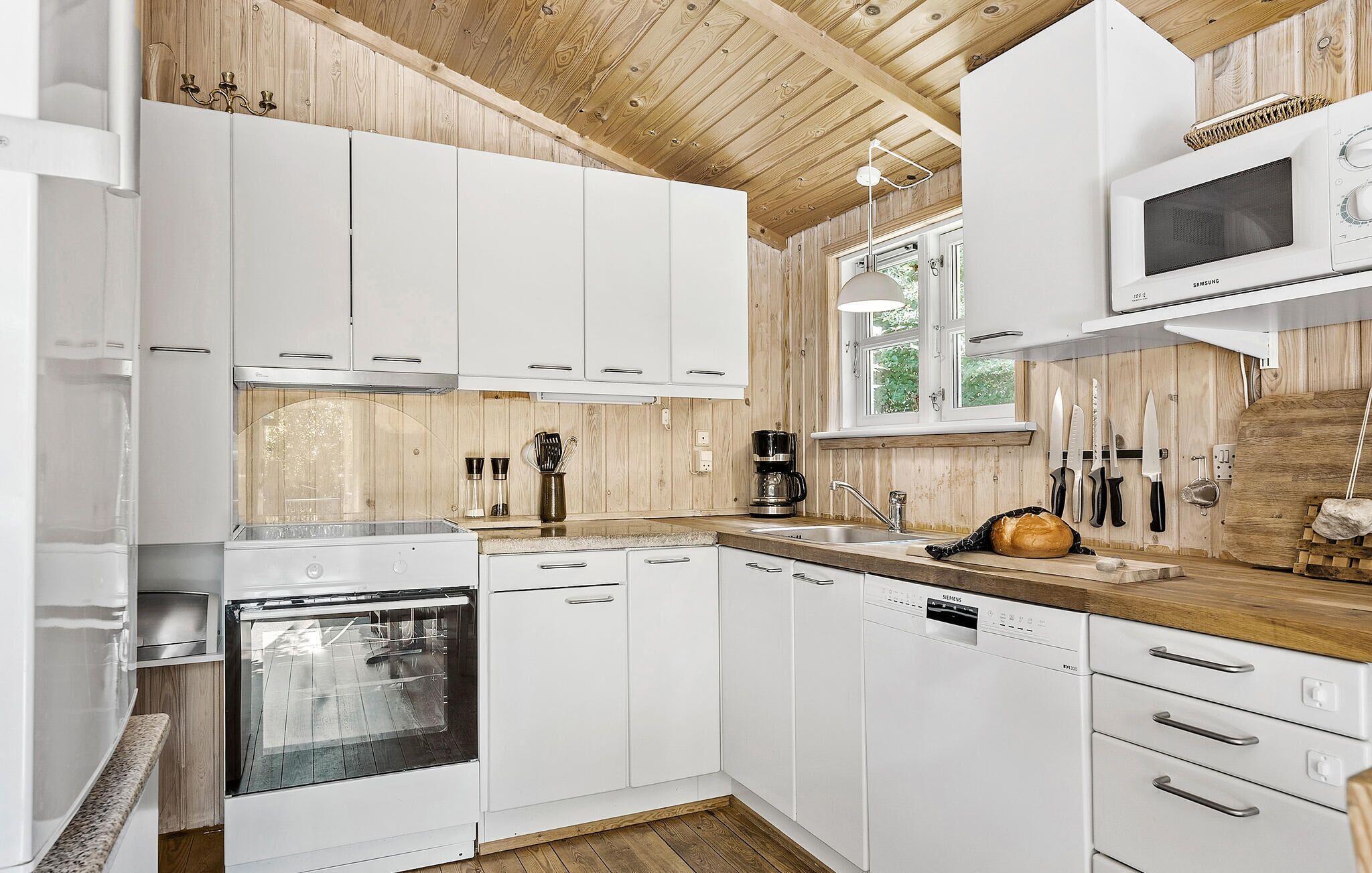 A modern kitchen with white cabinets, a built-in oven, a dishwasher, and a microwave.