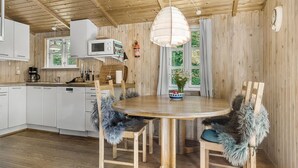 A cozy kitchen with wooden cabinets, a microwave, and a dining area with a round table and chairs. - 3 bedroom amazing home in Samsø (Samsø)
