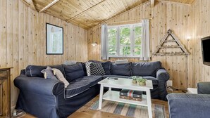 A cozy room with a sectional sofa, a small white table, and a window with curtains. - 3 bedroom amazing home in Samsø (Samsø)
