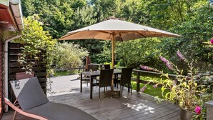 A wooden deck with a table and chairs, an umbrella, and a lounge chair. - 3 bedroom amazing home in Samsø (Samsø)