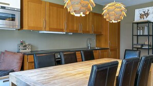 Una cocina moderna con armarios de madera, horno de acero inoxidable y un comedor con mesa de madera y sillas negras.