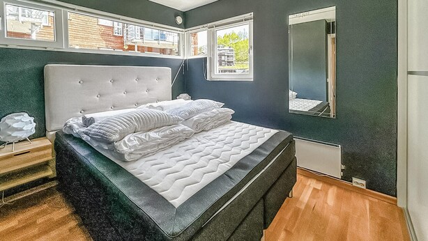 Un dormitorio con una cama grande, un cabecero, una ventana y un espejo.