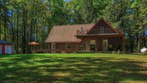 A rustic brick house with a sloped roof, a porch, and a small deck.
