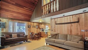 A cozy cabin interior with wooden walls, a dining area, and a kitchen.