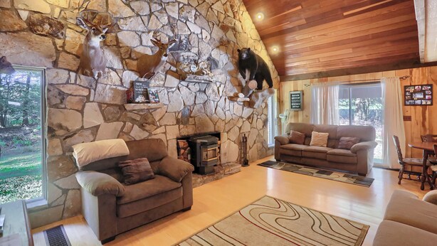 A cozy living room with stone walls, a fireplace, and a stone fireplace surround. There are two sofas and a coffee table.