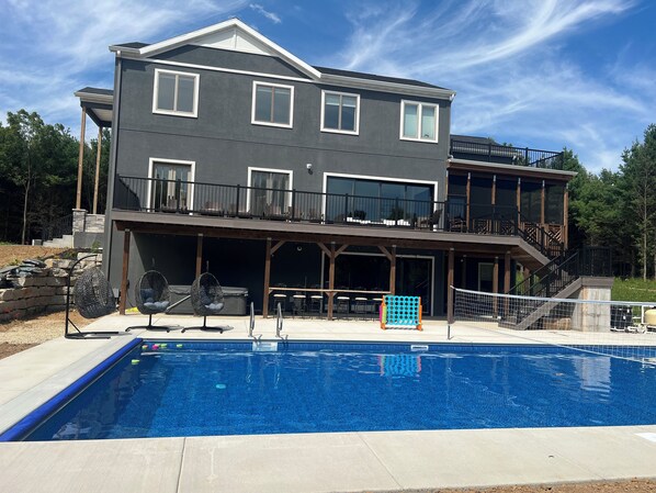 A two-story house with a pool, outdoor seating, and a balcony.