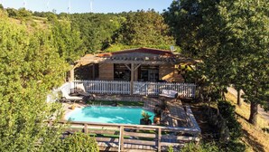 Una casa con piscina, rodeada por una terraza de madera y una valla blanca.