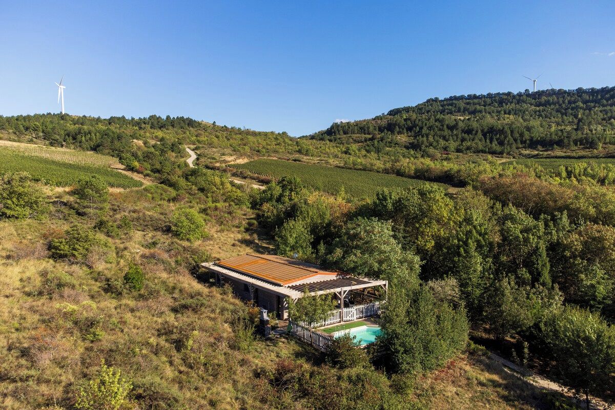 A secluded house with a pool, surrounded by lush greenery and hills.