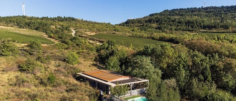 Una casa aislada con piscina, rodeada de abundante vegetación y colinas.