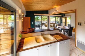 A modern kitchen with a wooden countertop, two sinks, and a view to an outdoor patio.