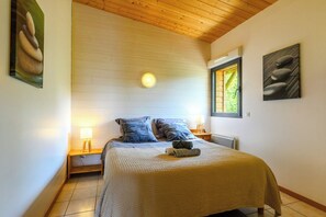 A bedroom with a bed, two bedside lamps, a window, and artwork on the walls. - Lodge & piscine privée sur domaine viticole (Roquetaillade-et-Conilhac)