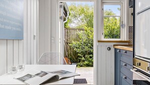 A kitchen with white walls, a blue cabinet, a window, and a door leading outside. - 1 bedroom nice apartment in Skagen (Skagen)