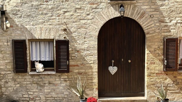 A stone building with a wooden door, a window with shutters, and potted plants. - R003 - Recanati, delightful three-room apartment in the center (Recanati)
