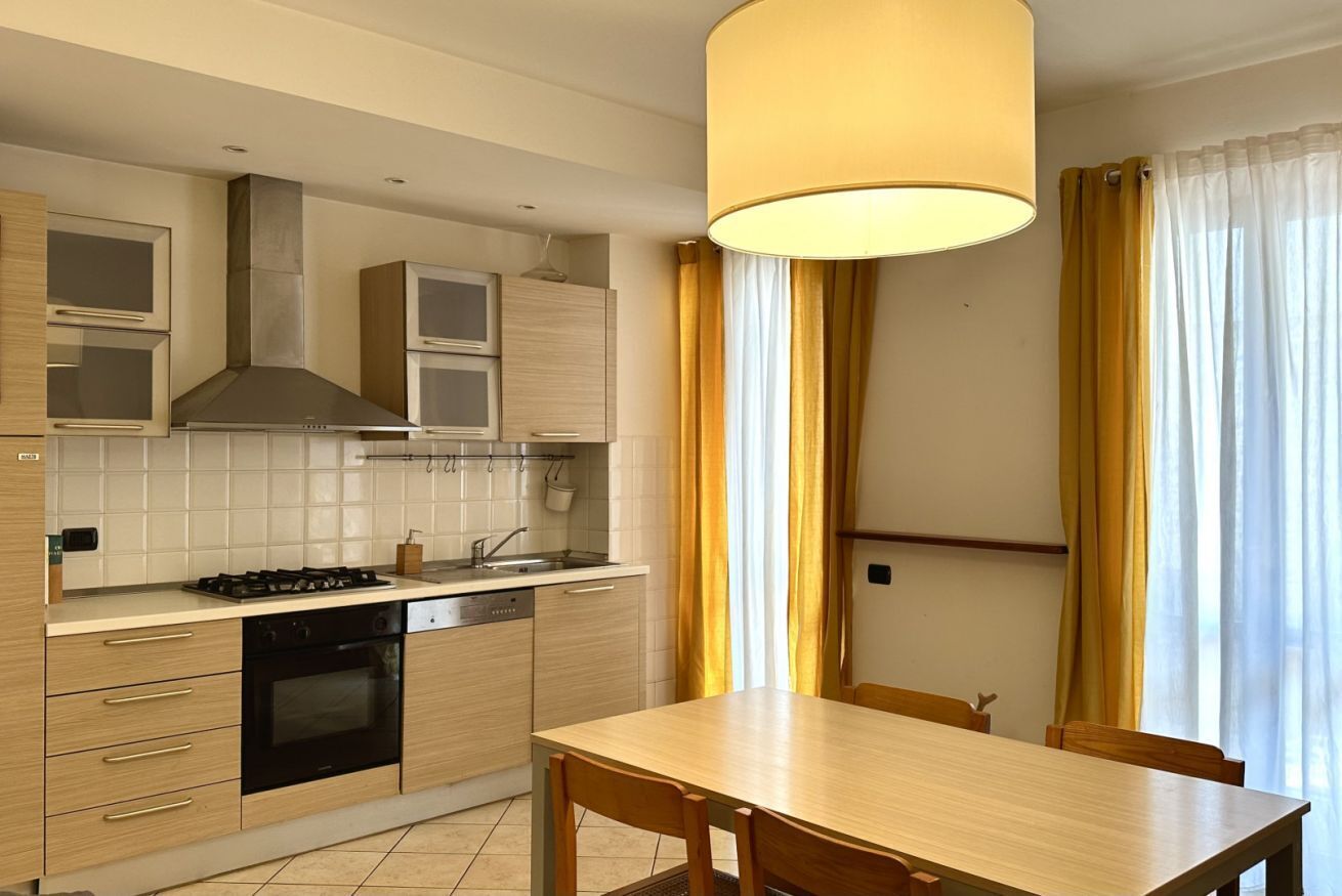 Une cuisine moderne avec une table et des chaises, une cuisinière, un four et des placards.