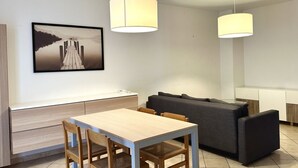 A modern living room with a dining table, sofa, and two pendant lights. - R003 - Recanati, delightful three-room apartment in the center (Recanati)