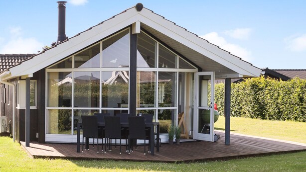 A conservatory with a glass roof, a wooden deck, and a seating area with tables and chairs. - Stunning home in Haderslev with WiFi (Haderslev)