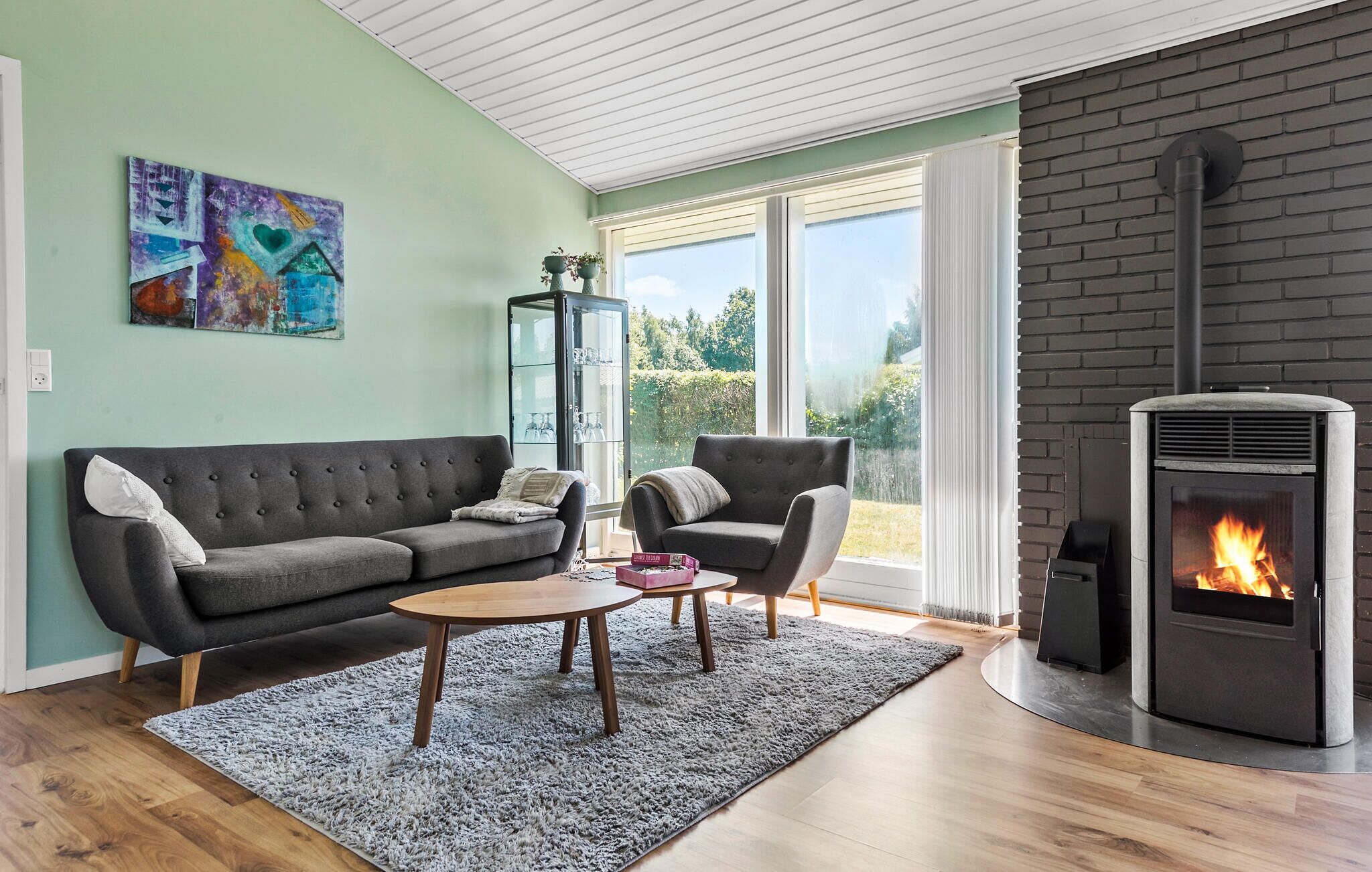 Un salon comprenant un canapé, un fauteuil, une table basse, une cheminée et des œuvres d’art accrochées au mur.