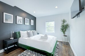 A modern bedroom with a green bed frame, white bedding, a nightstand with a lamp, and a potted plant. - DC`s premier group home 5 bedrooms, 11 guests, EV charging, free parking (Washington)