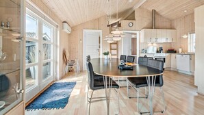 A modern kitchen with wooden cabinets, a dining area with a round table and chairs, and a visible clock on the wall. - Nice home in Tarm with sauna (Tarm)