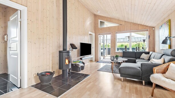 A modern living room with a wood-paneled interior, a fireplace, a sofa, and a television. - Nice home in Tarm with sauna (Tarm)