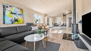 A spacious living room with a grey sofa, a round coffee table, and a large painting on the wall. - Nice home in Tarm with sauna (Tarm)