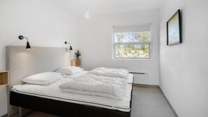 A bedroom with a bed, two bedside lamps, a window with a view of trees, and a framed picture on the wall. - 4 bedroom awesome home in Frørup (Frørup)