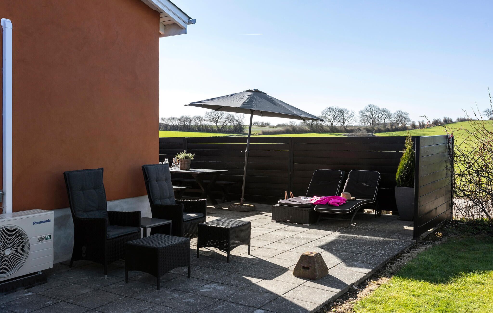 An outdoor patio with a table, chairs, and a large umbrella.