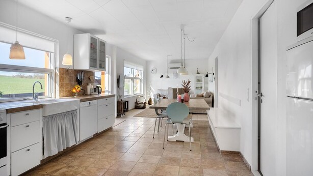 A spacious kitchen with a large window, a dining area with a table and chairs, and a view of the outdoors. - 4 bedroom awesome home in Frørup (Frørup)