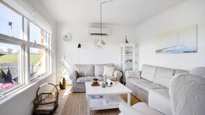 A modern living room with a white sofa set, a coffee table, a bookshelf, and a painting on the wall. - 4 bedroom awesome home in Frørup (Frørup)