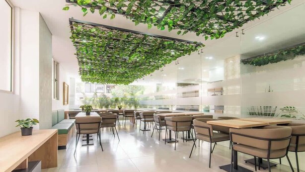 Un intérieur moderne agrémenté d’un jardin suspendu au plafond, de coins salon et d’un mur en verre.