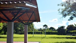 A covered pavilion with a metal roof, surrounded by a well-maintained lawn and trees. - finca el arrullo (Armenia)