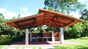 A covered outdoor area with a brick barbecue and a wooden pergola structure. - finca el arrullo (Armenia)