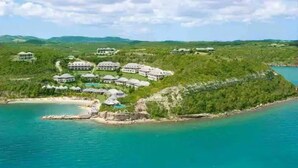 A coastal resort with multiple villas, a beach, and a clear view of the surrounding landscape.