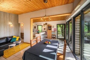 A modern interior with a dining area, kitchen, and large windows.