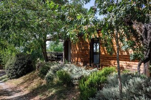 Una cabaña de madera rústica rodeada de follaje denso y un sendero de grava.