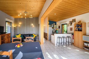 A room with a bed, a dining area with a table and chairs, a kitchenette, and a living area with a sofa and chairs.