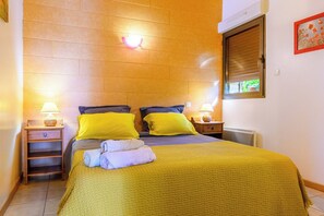 Een slaapkamer met een bed, twee nachtkastjes, een wandlamp en een raam met jaloezieën.